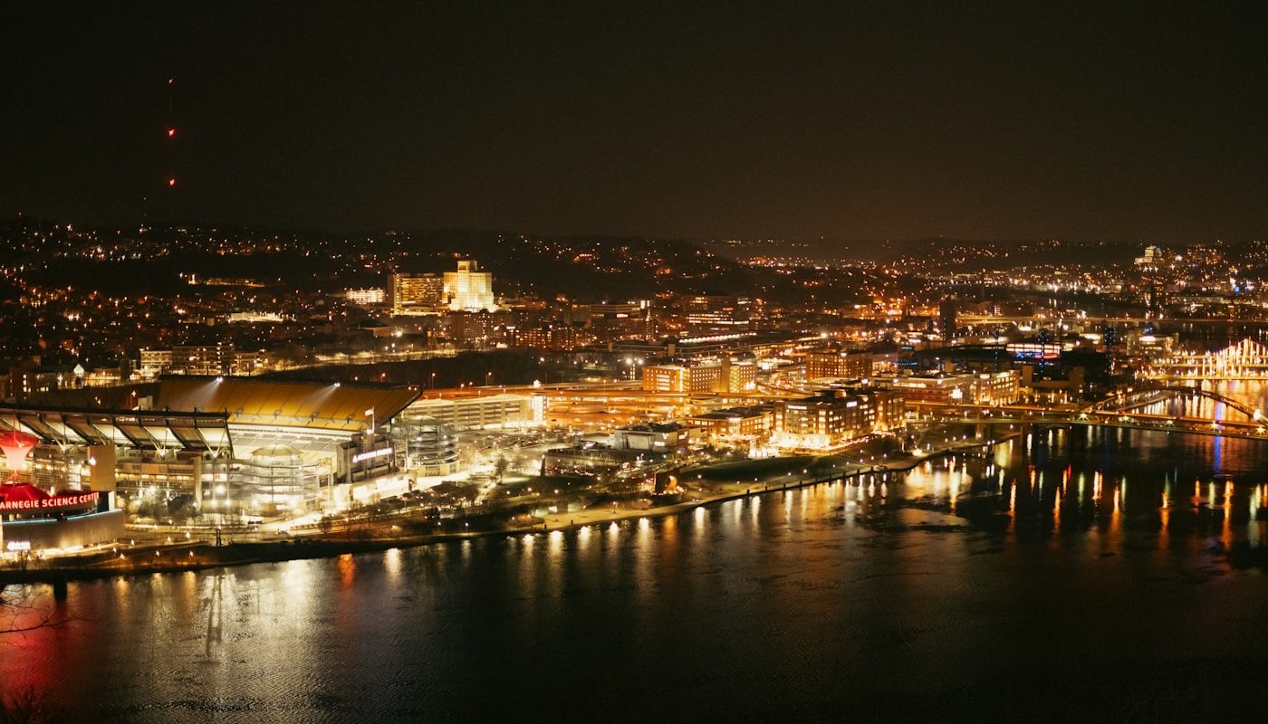 Nighttime view of a city skyline with harbor lights.