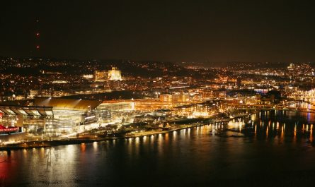 Nighttime view of a city skyline with harbor lights.