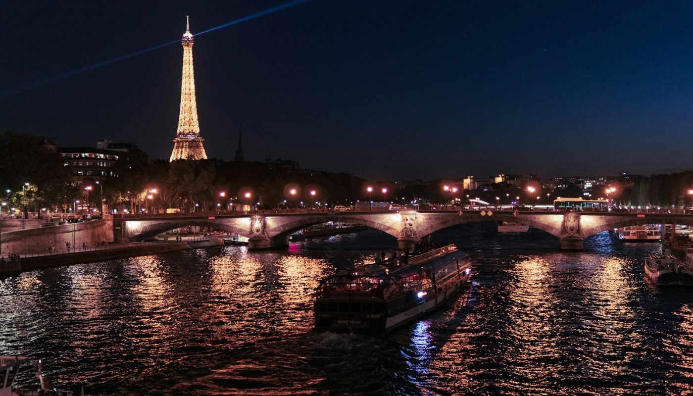 boat on river near Eiffel tower at nighttime