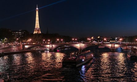 boat on river near Eiffel tower at nighttime